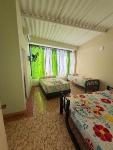 a room with two beds and a window with green curtains at Villa Alejandro in Melgar