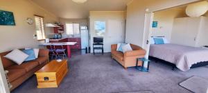 a bedroom with a bed and a couch and a kitchen at Cedar Cottage in Takaka