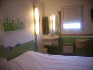 Un baño con una cama, un lavabo y un espejo. en ibis budget Remiremont, en Remiremont 20 fotos más