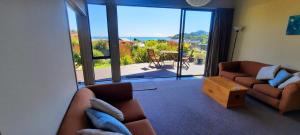a living room with two couches and a view of a patio at Cedar Cottage in Takaka