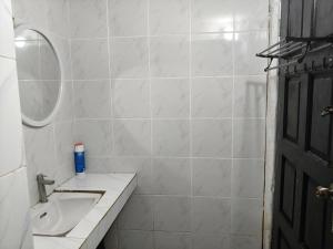 a white bathroom with a sink and a mirror at Halwa Homestay in Semporna
