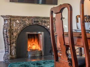 a stone fireplace with a fire in it at Groudd Hall in Cerrigydrudion