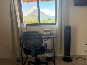 a desk with a chair in front of a window at Cabin Casove in El Castillo de La Fortuna