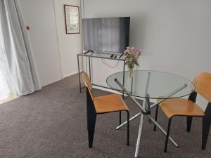 a glass table with two chairs and a vase with flowers at Marigold in Manurewa in Auckland +4 photos
