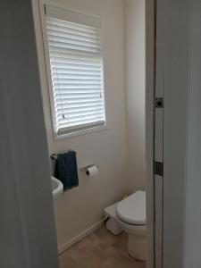 a white bathroom with a toilet and a window at Marigold in Manurewa in Auckland