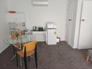 a kitchen with a glass table with chairs and a refrigerator at Marigold in Manurewa in Auckland