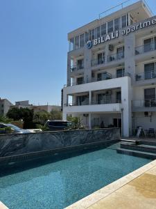 a hotel with a swimming pool in front of a building at Bilali Apartments in Ulcinj