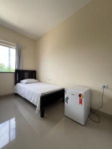 a bedroom with a bed and a refrigerator at Hotel Brilhante 2 in Itacarambi
