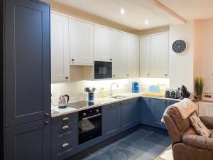 a kitchen with blue cabinets and a sink at The Boathouse in Appledore