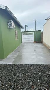 a green building with a white garage door and a driveway at Canastra House in Delfinópolis
