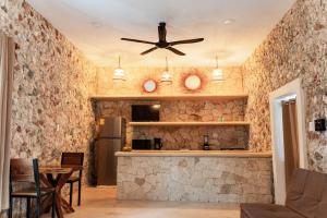 a kitchen with a ceiling fan and a stone wall at Villa Carulio in Ebtún