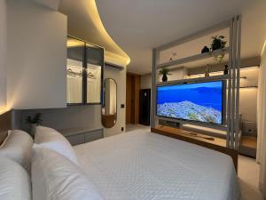 a bedroom with a large bed and a flat screen tv at Sky Designer Alphaville - 1611 in Barueri