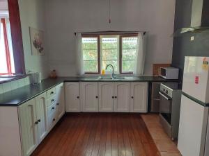 a kitchen with white cabinets and a black counter top at Forest Edge Cottage Dwellingup in Dwellingup +13 photos