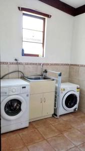 a kitchen with a washing machine and a sink at Forest Edge Cottage Dwellingup in Dwellingup
