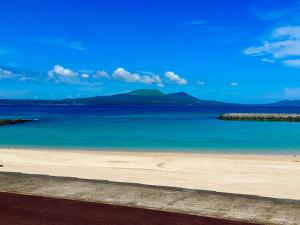 a beach with blue water and mountains in the background at イトノ-itono- in Goto