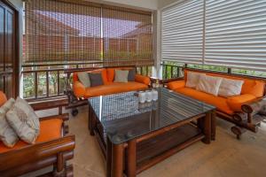 a living room with orange chairs and a glass table at Malee Beach C6 in Phra Ae beach