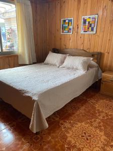 a large bed in a room with wooden walls at Cabaña Peuño in Chovellén