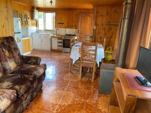 a kitchen with a couch and a table in a room at Cabaña Peuño in Chovellén