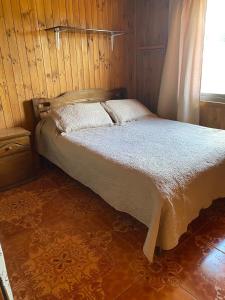 a bed in a wooden room with a window at Cabaña Peuño in Chovellén