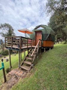 a small house with an umbrella on the grass at Eclipse de luna Guatavita in Guatavita