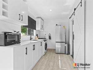 a kitchen with white cabinets and a refrigerator at Iluka Magic in Iluka +7 photos