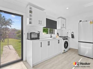 a kitchen with white cabinets and a refrigerator at Iluka Magic in Iluka
