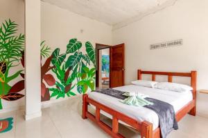a bedroom with a bed with a mural on the wall at Hotel talú tayrona in El Zaino