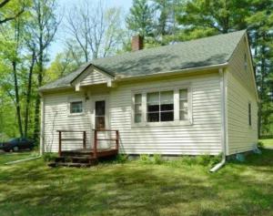 a small white house with a porch in a yard at Yellow Barn House in Danbury