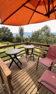 two tables and chairs on a deck with an umbrella at Eclipse de luna Guatavita in Guatavita