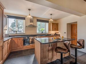 a kitchen with wooden cabinets and a large island at Groudd Hall in Cerrigydrudion +25 photos