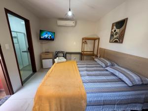 a bedroom with a large bed and a television at Suíte Peixe Espada in Praia do Forte