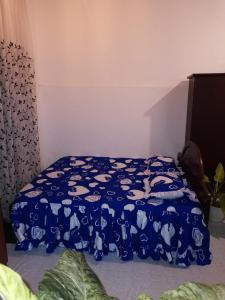 a bedroom with a blue comforter with cats on it at Bloo Ivy-Peradeniya in Peradeniya