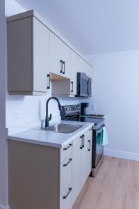 a kitchen with white cabinets and a sink at Honeycomb Suite in Riverview