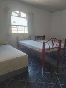 two beds in a room with a window at chácara Cantagalo in Caraguatatuba