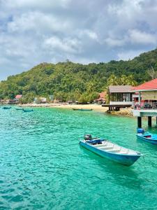 a boat sitting in the water next to a beach at Summer village in Kampong Pasir Hantu