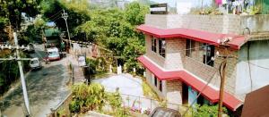 a building with a red roof on a city street at ViDi Hotel Serene Point ! Kalimpong in Kalimpong