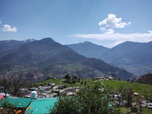 a town on a hill with mountains in the background at ONLY CAFE Hotel in Chopta