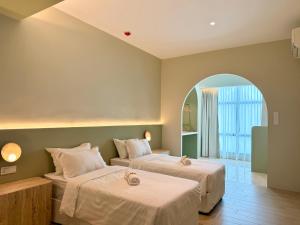 a bedroom with two beds and an arched window at Asimmy Hotel in Kampong Gurun