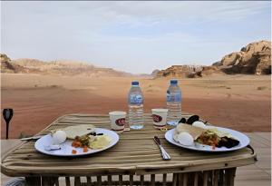a wooden table with plates of food and bottles of water at The bubble camp in Wadi Rum
