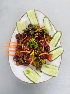 a plate of food with meat and vegetables and cucumbers at Villa Indeewara in Welipenna East