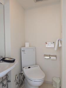 a white bathroom with a toilet and a sink at Kagetsuen in Hakone