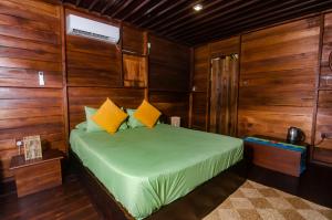 a bedroom with a green bed with wooden walls at Raintree Haven in Dambulla