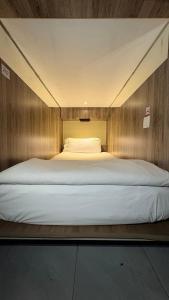 a large white bed in a small room at The Hide Hostel Canggu in Canggu