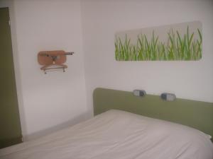 Un dormitorio con una cama y un cuadro de césped. en ibis budget Remiremont, en Remiremont