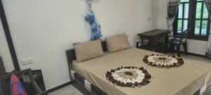 a bed with two pillows on it in a room at Nilaveli Beach Rooms in Nilaveli