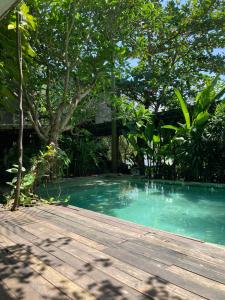 a swimming pool with a wooden deck and trees at The Hide Hostel Canggu in Canggu