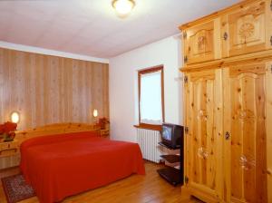 a bedroom with a red bed and a wooden cabinet at Hotel Florian in Nus