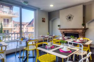 een restaurant met tafels en stoelen en een open haard bij Zenitude Hôtel-Résidences Les Terrasses du Lac in Évian-les-Bains