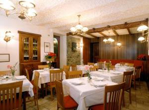 a dining room with tables and chairs with white tablecloths at Hotel Florian in Nus +29 photos