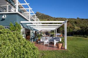 a patio with two chairs and an umbrella at Poseidon Guest House in Hout Bay